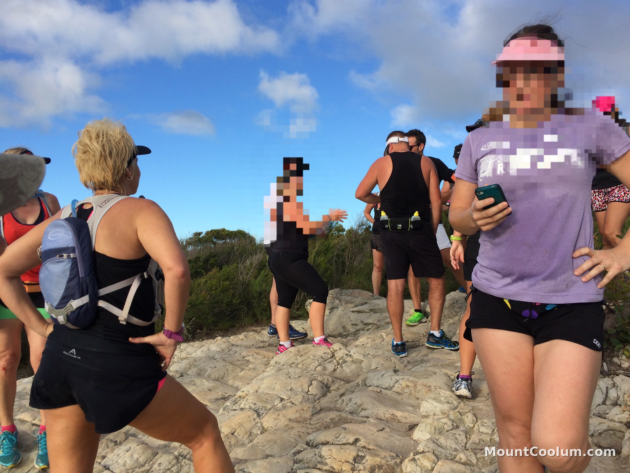 A group of walkers resting together on the rocky summit outcrop of Mount Coolum